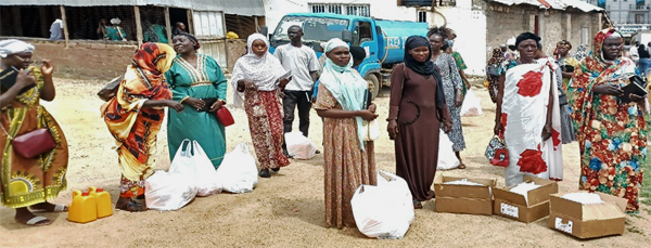 A line of women wait in line for oil, with sacks of food at their feet in Juba